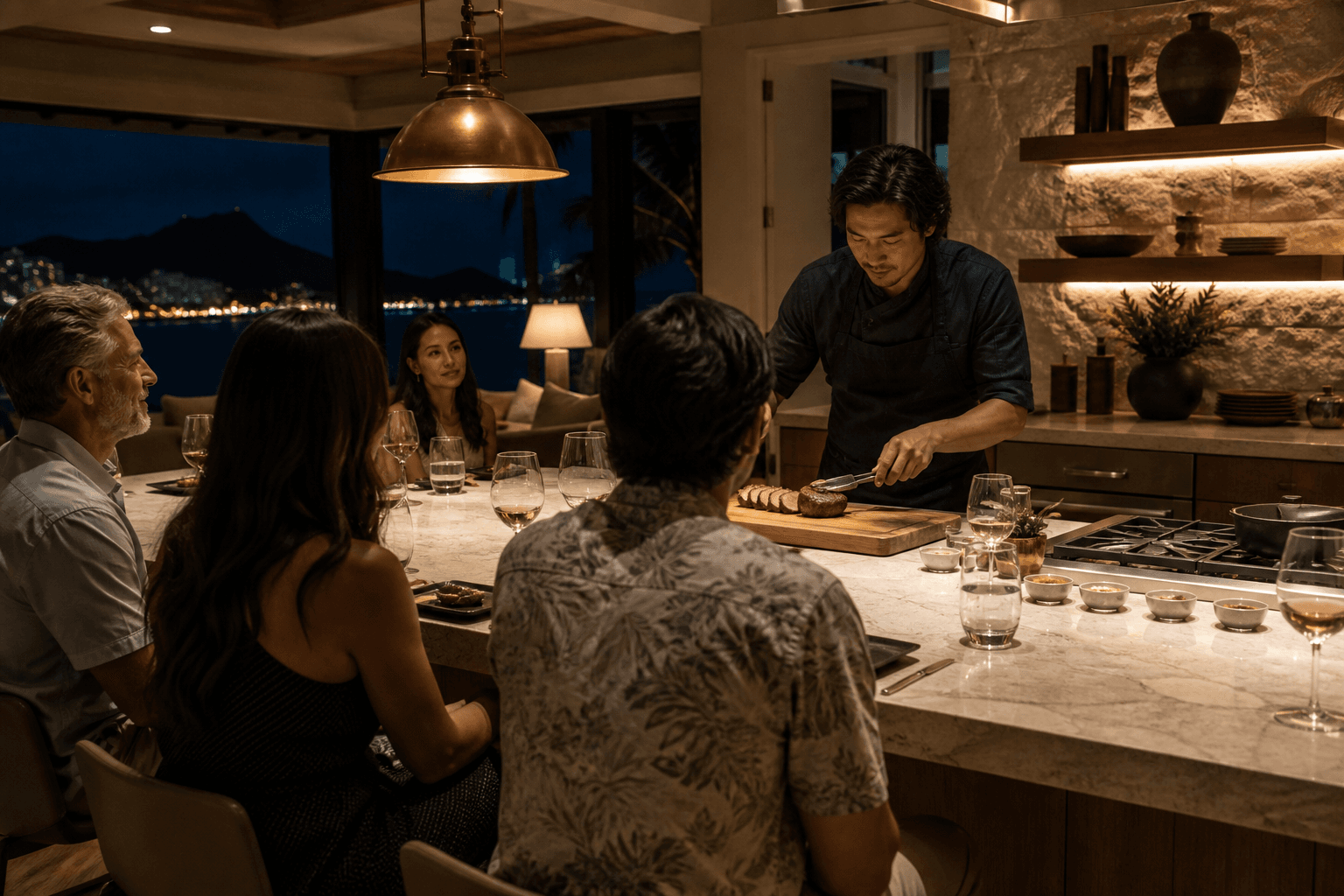 Guests at a Kahala kitchen island at night watching a sear — not a restaurant pass.