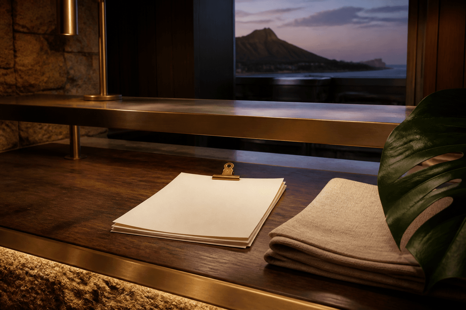 Unused ivory papers under a brass clip on a Kahala koa pass at dusk, Diamond Head faint.