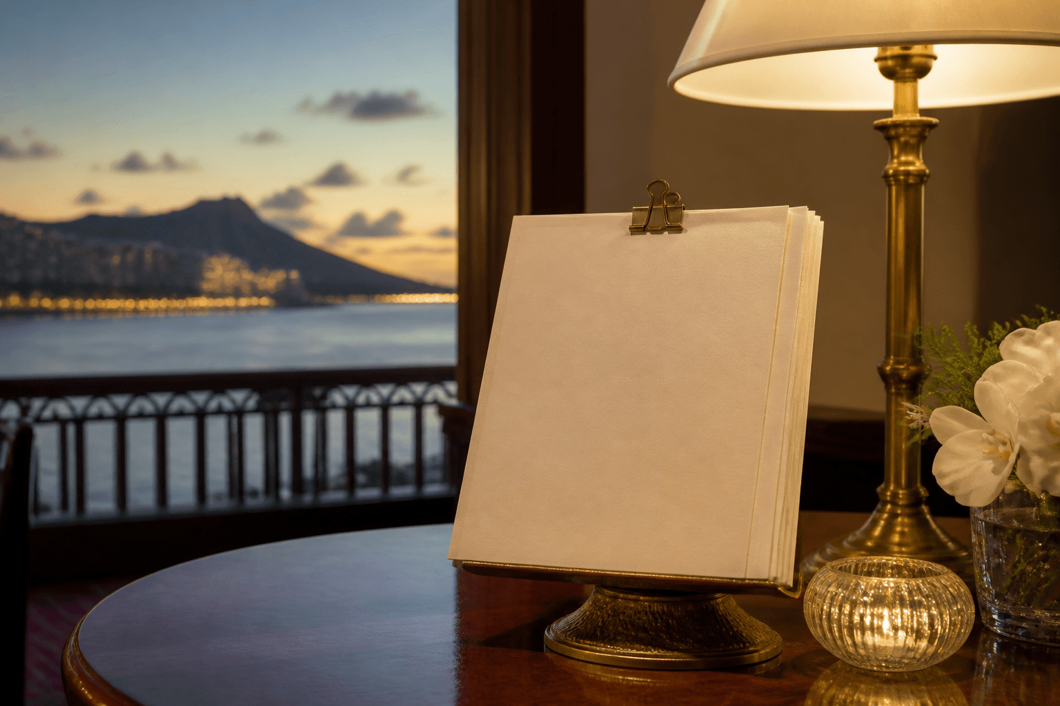 A stacked set of blank cream URL cards on a Kahala dining table at dusk, brass clip, Diamond Head faint.